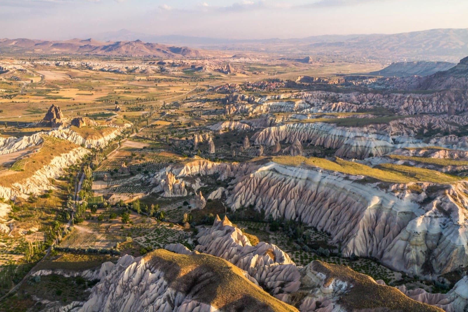 Hot-air balloons rising over the Cappadocia fairy chimneys at sunrise